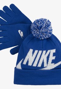 Kék kötött sapka fehér "NIKE" logóval, tetején kék-fehér bojttal. Kék kötött kesztyűk kis fehér "NIKE" logóval.