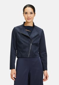 Marinblått cropped jacka i mjukt mockaliknande material med notchkrage och framdragkedja. Minimalistisk design med rena linjer.