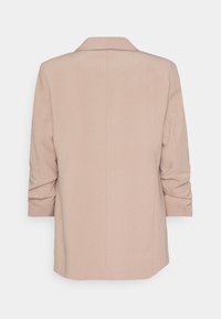 Blazer da donna beige chiaro con un design strutturato, dotato di colletto a punta, maniche arrotolate e una cucitura posteriore singola.