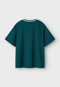 Camiseta de manga corta en color teal, hecha de un tejido texturizado, con un cuello blanco acanalado y un corte holgado, con costuras visibles en los bordes.