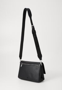 Sac bandoulière en cuir noir avec une finition texturée, doté d'une poche zippée à l'avant et d'une sangle réglable. Des accents en métal argenté rehaussent le design.
