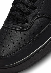 Sneaker nera in pelle con upper texturizzato, perforazioni per la traspirabilità e suola in gomma nera con bordo liscio.