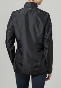 Black, lightweight jacket with a high collar, smooth texture, and zippered pockets. Features sleek, tailored fit and reflective accents.