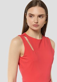 Czerwona top bez rękawów z wysokim dekoltem i wycięciem na ramieniu. Miękka, gładka tkanina z dopasowanym krojem.