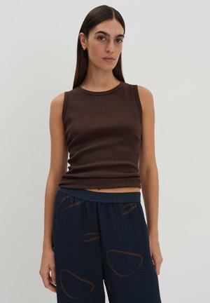 Brown sleeveless ribbed top with a round neckline, paired with navy blue patterned pants featuring brown abstract shapes. Smooth texture.