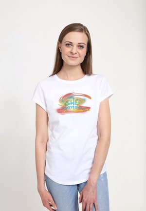 Hvid kortærmet t-shirt med et farverigt "SHE HULK" grafik med snurrende, multifarvede mønstre på forsiden. Bæres med blå jeans.