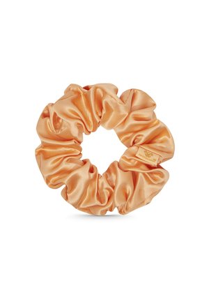 Satin haarelastiek in een zachte perzik kleur, met een verzameld ontwerp en een gladde textuur. Inclusief een klein merklabel.