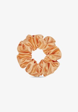 Satinowy scrunchie w miękkim odcieniu brzoskwiniowym, posiadający marszczoną konstrukcję z gładką fakturą. Zawiera małą metkę z logo.
