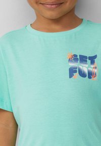 Turqooise katoenen t-shirt met een kleurrijke "GET FUN" graphic met een zon- en surfplankontwerp. Korte mouwen, ronde hals.
