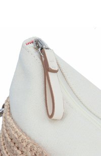 Bolsa de canvas blanca con acentos tejidos en beige. Cuenta con un cierre de cremallera y una pestaña de tira de cuero marrón. Superficie texturizada y diseño limpio.