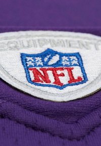 Nahaufnahme eines gestickten NFL-Schildlogo-Patches auf einem lila Stoffhintergrund.