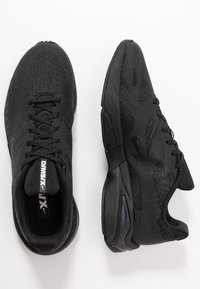 Black athletic shoes with a textured, reptile-like upper, featuring a lace-up design and cushioned soles. Sleek shape and minimal branding.