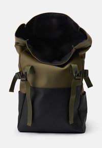 Sac à dos étanche à rabat en vert olive et noir. Comprend des bretelles ajustables, une base robuste et une finition lisse et texturée.