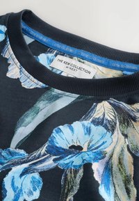 Dres z kwiatowym wzorem na ciemnym tle, z niebieskimi kwiatami i zielonymi liśćmi. Okrągły dekolt z kontrastowym ściągaczem.