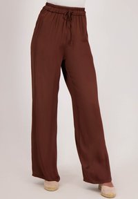 Bruine, lichte, wijde broek met een elastische tailleband en trekkoord. Gladde textuur, minimalistisch ontwerp en geen zichtbare patronen of accenten.