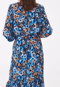 Abito floreale con sfondo nero, caratterizzato da fiori blu e arancioni. Tessuto morbido, maniche lunghe, elasticizzato in vita e orlo arricciato.