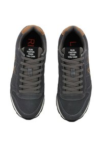 Scarpe da ginnastica grigie con dettagli marroni, tessuto texturizzato e lacci grigi. Le etichette all'interno dicono: "CORRI PIÙ VELOCE DI QUANTO PUOI."
