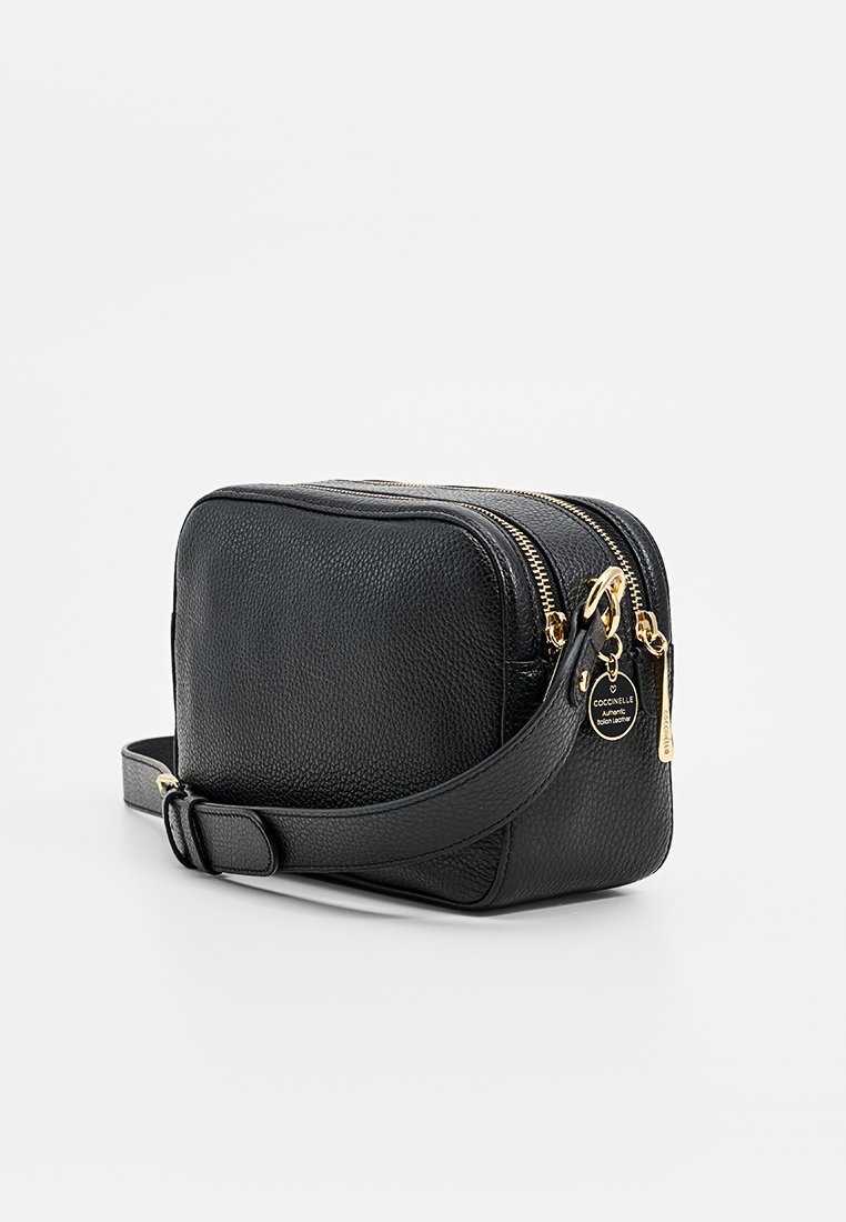 Sac à bandoulière en cuir noir avec surface texturée, matériel doré, double zippers et une bandoulière détachable. Forme rectangulaire compacte.