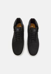 Zwarte high-top sneakers van suede en leer, met een grijze rubberen zool, ronde veters en een logo op de tong.