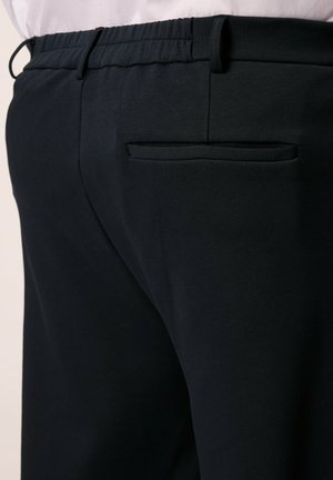 Schwarze Hose mit elastischem Bund und Gesäßtasche, aus einem weichen Material mit glatter Textur und enganpassendem Design.