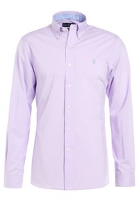 Ljuslila bomullsskjorta med knappar och krage, vita knappar och en liten grön broderad logotyp på vänster bröst. Långa ärmar.