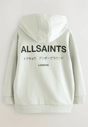 Ljusgrå huvtröja med stor svart text "ALLSAINTS" och ytterligare text på japanska, "LONDON", tryckt nedanför. Mjuk bomullsblandning.