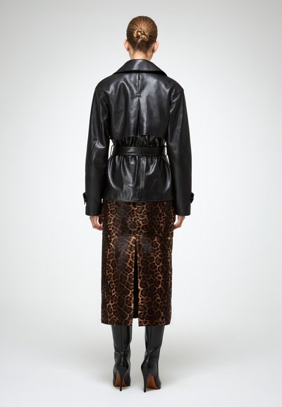 Zwarte leren jas met een riem in de taille, gecombineerd met een leopardenprint kokerrok, met een zijsplijt en kniehoge zwarte laarzen.