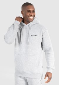 Grauer Pullover-Hoodie aus weichem Stoff, mit einer frontalen Kängurutasche, Kapuze mit Kordeln und gesticktem "SMILODOX"-Logo auf der Brust.