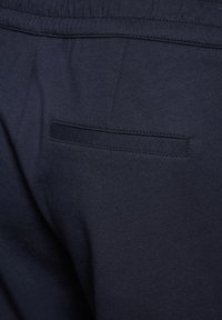 Marina blå joggers med en mjuk bomullstextur, med ett elastiskt midjeband och en liten, diskret bakficka.