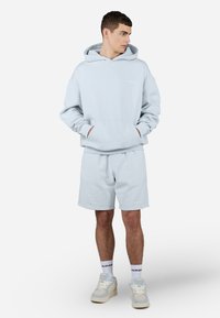 Lys blå hettegenser med frontlommer, kombinert med matchende shorts. Laget av myk stoff, har ribbede mansjetter og logo detaljer.