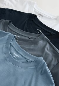 Four crew-neck t-shirts stacked: white, navy, dark gray, and light blue. Made of smooth cotton, showcasing a simple design and label.
