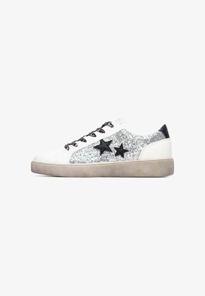 White sneaker with silver glitter accents and black star designs. Features black laces and a textured gray sole. Smooth leather material.
