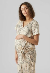Vestito avvolgente per maternità in beige chiaro con motivo paisley. Maniche corte, scollo a V e dettaglio con nodo frontale. Tessuto morbido con un design fluido.