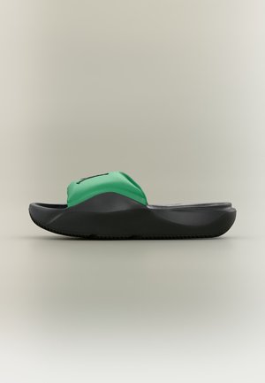 Une sandale slide verte et noire avec une semelle épaisse et profilée ainsi qu’un bout ouvert, vue de côté sur fond neutre.
