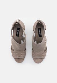 Sandales beiges en daim DKNY à bout ouvert, empeigne en mesh, brides à la cheville et fermetures à boucle argentée, vues de dessus.