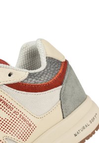 Baskets avec une combinaison de couleurs beige, rouge et gris ; textures en mesh et en daim ; présentent des accents perforés et une semelle rembourrée portant l'inscription "NATURAL SOFT."