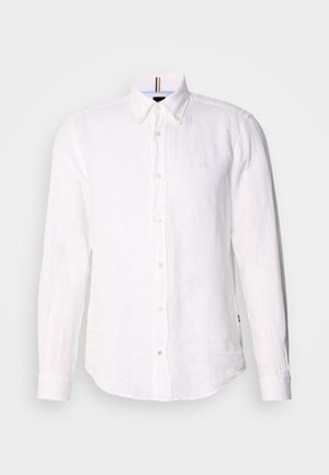 Camisa de linho branca com mangas longas, frente abotoada e um logotipo subtil no peito. Apresenta um colarinho estruturado e uma bainha curved.