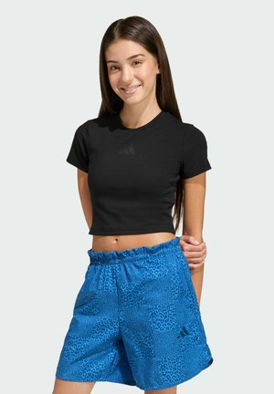 Camisa negra corta con mangas cortas y un logo sutil, combinada con pantalones cortos azules con estampado de leopardo y cinturilla elástica.