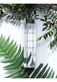 Transparante cilinder flacon met toner en een zilveren dop. Het etiket zegt "Botanical Toner" en is omringd door groene varens en bladeren.
