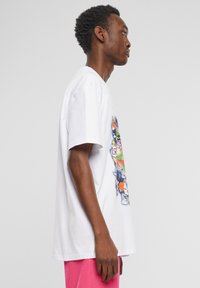 Hvid bomulds t-shirt med et farverigt grafisk print af tegneseriefigurer, korte ærmer og en afslappet pasform.