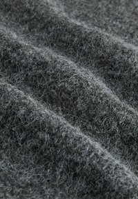 Grå tekstureret stof med en blød, fuzzy overflade, der har en blanding af korte og lange fibre, arrangeret i naturlige bølger.