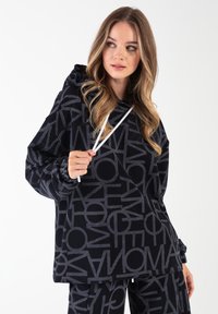 Czarna bluza z kapturem z wyraźnym szarym wzorem liter, wyposażona w kaptur ze ściągaczem, długie rękawy i luźny krój. Materiał jest miękki i gładki.