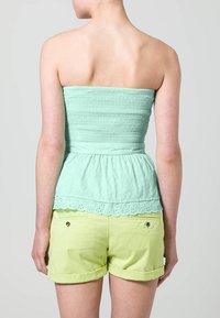 Top verde menta senza maniche con smocking testurizzato e orlo in pizzo a occhiello, abbinato a pantaloni corti verdi arrotolati con tasche posteriori e dettagli con bottoni.
