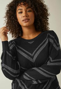 Maglione nero a maglia con strisce diagonali argento, caratterizzato da maniche a sbuffo e scollo rotondo. Texture morbida e design aderente.