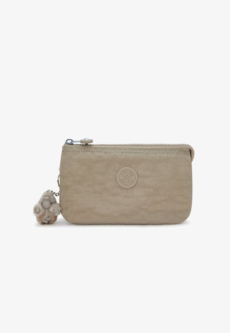 Pochette rectangulaire beige avec fermeture éclair, patch logo rond à l'avant et petit porte-clés singe en peluche attaché au curseur de la fermeture éclair.