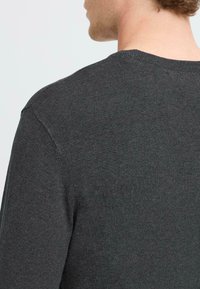Suéter de color gris oscuro con cuello redondo y mangas cortas. El material parece suave y liso, con una textura de punto fino.