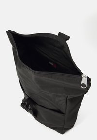 Svart ryggsekk med rulltoppsdesign. Laget av strukturert stoff, har en glidelåsåpning, en frontlomme og justerbare detaljer.