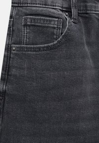 Los vaqueros de mezclilla gris oscuro presentan un bolsillo frontal con detalle de costura y un remache metálico, mostrando un acabado de tela suave y texturizado.