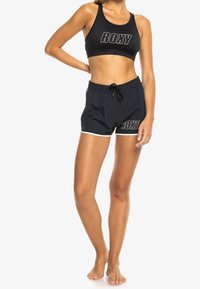 Svart sportbh med "ROXY"-logotyp och matchande svarta shorts med vit trim och dragsko i midjan. Lättviktsmaterial med stretch.