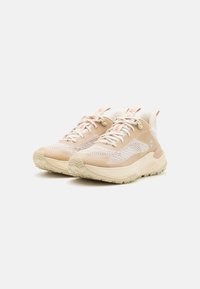 Helle beige Sportschuhe mit einem strukturierten Mesh-Obermaterial, weißen Akzenten, gepolsteter Sohle und multidirektionalem Profil für besseren Halt.